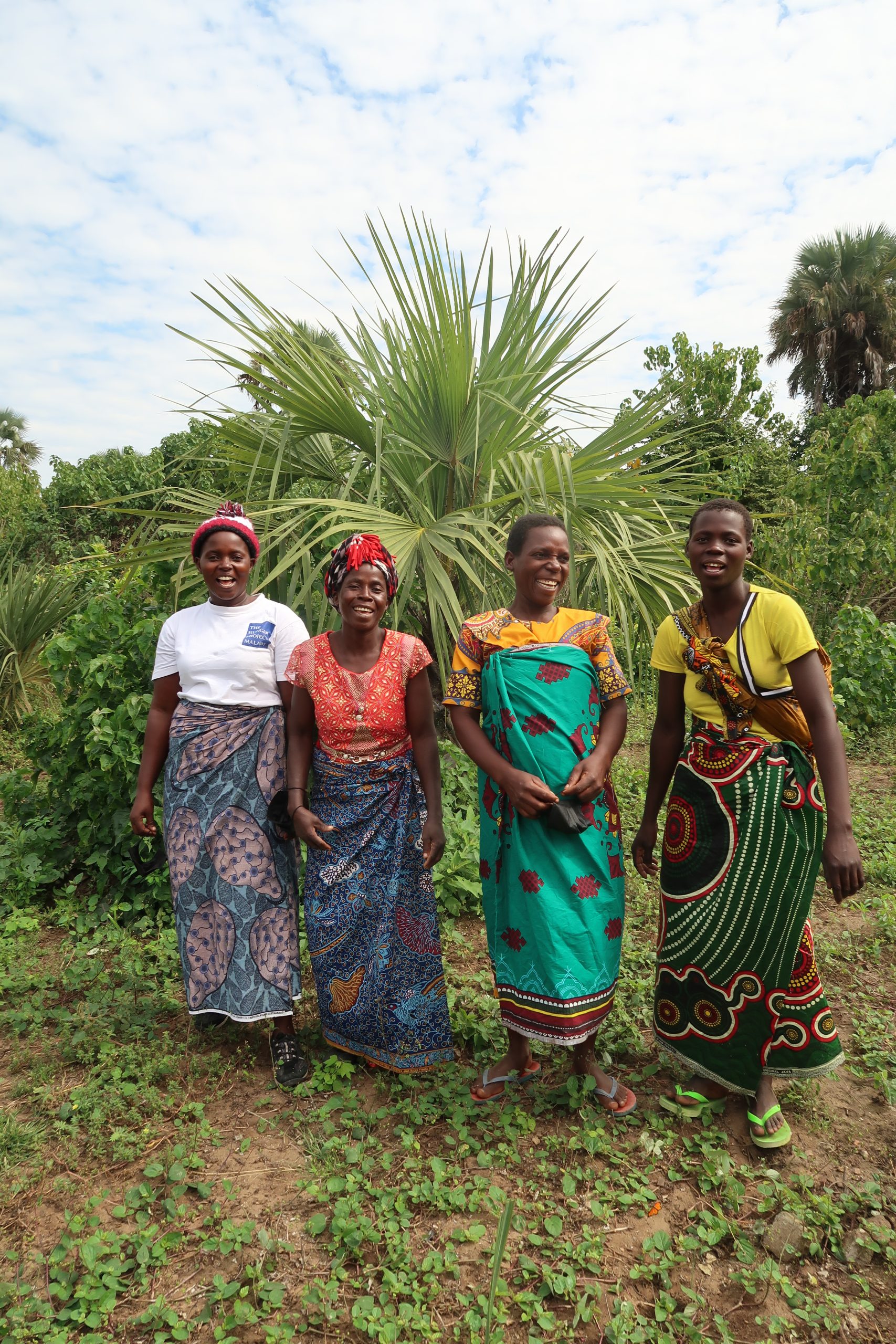 Group of women in colourful clothing, standing in a field in Majete, Malawi